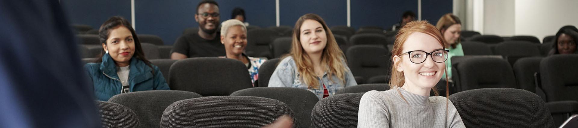 A group of students smiling during a lecture