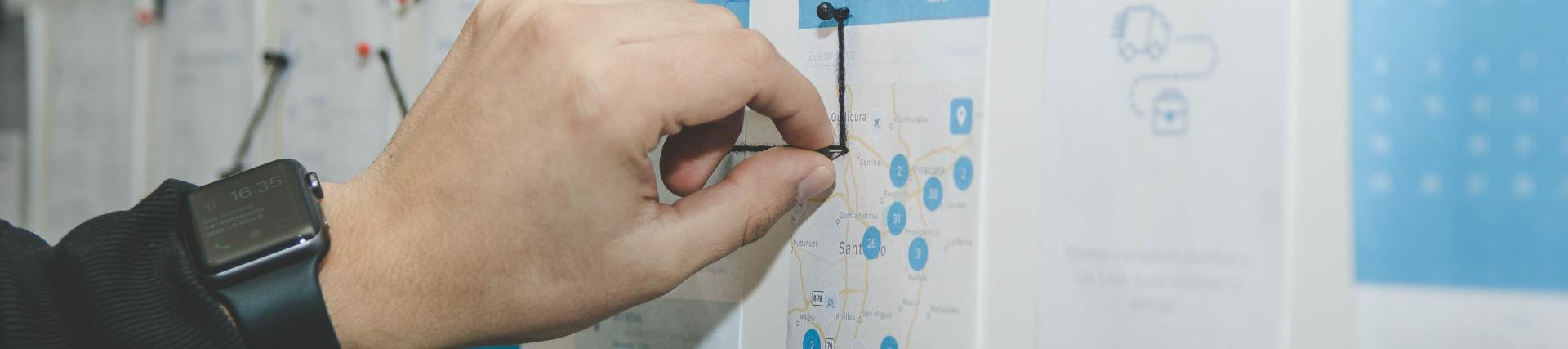 Hand placing a pin on a chart