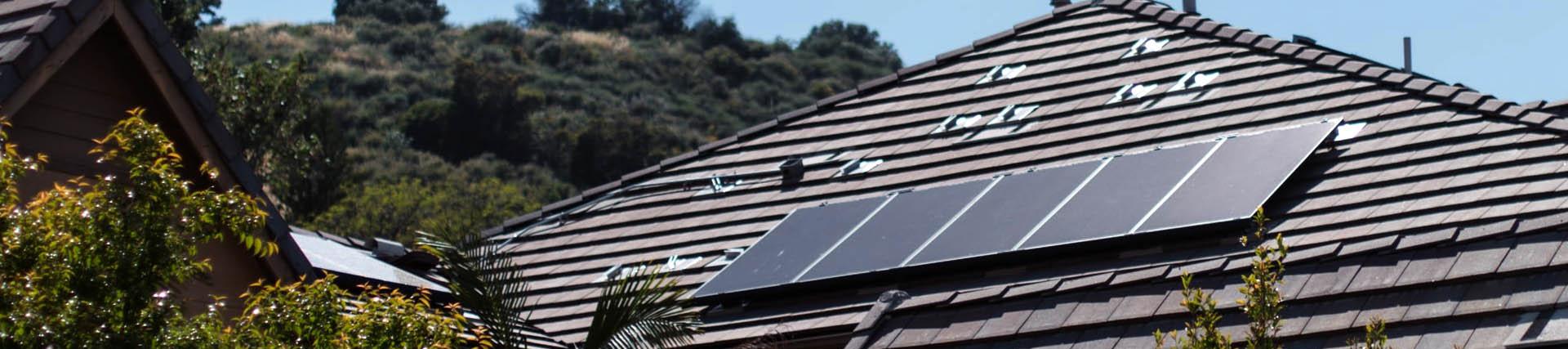 Five solar panels attached to a rooftop pictured on a sunny day