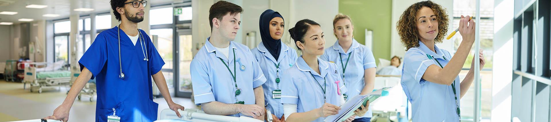 A mixed group of student nurses wearing blue uniforms