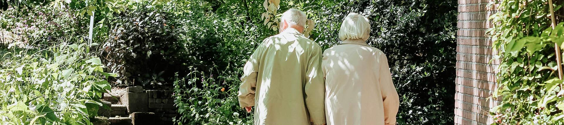 Two older people walking in the garden of their care home