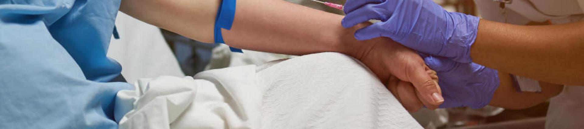 A close up view of a nurse setting up a peripheral venous catheter