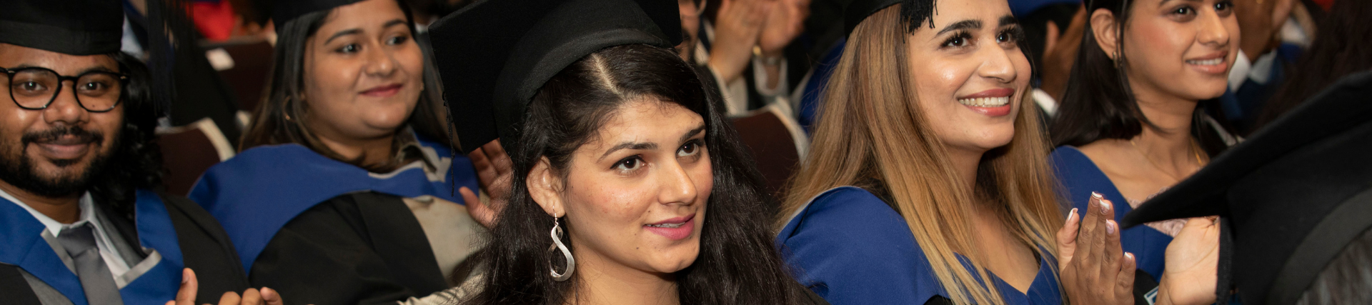 Graduates sitting and smiling at the University of West London's graduation ceremony