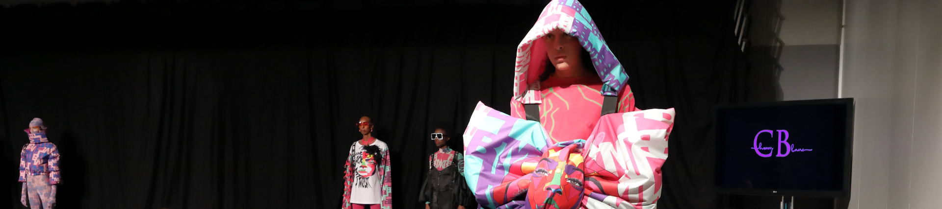 Fashion students at an ARTSFEST fashion show in vibrant outfits.