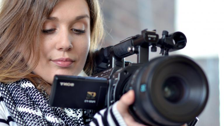 A camera operator, focusing her video camera