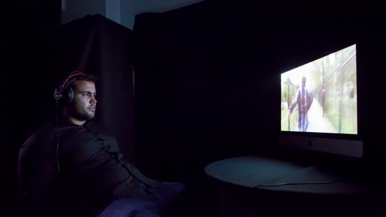 A man watching a film in a private booth