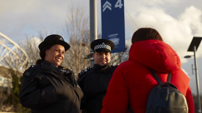 Two police officers talking to a member of the general public outside.