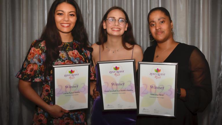 Olivia Parker-Smith, Prema Rebekah Kaur Sembi-Harding and Nekshia Alcee are holding winners certificates in formal dress at the Zest Quest Asia Awards ceremony.