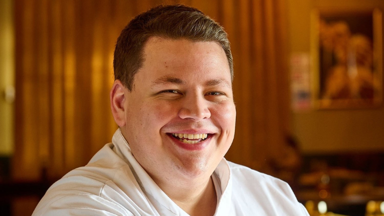 Chris Hurter has short brown hair and is smiling, wearing white chef clothing.