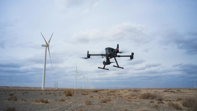 A drone flying in front of a wind turbine