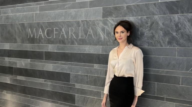 Mia Stapleton posing by a sign inside the Macfarlanes offices