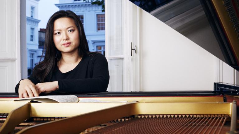 Annie Yim leaning on a piano