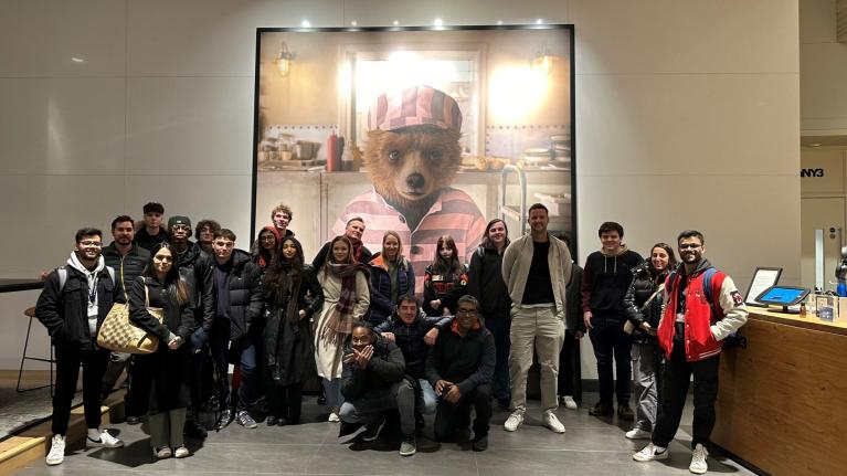 LSFMD students stood in front of a large picture of Paddington, a VFX creation of Framestore, in their offices.