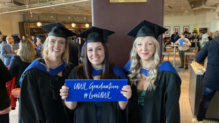 Three Midwifery graduates from CNMH pose at their ceremony, wearing caps and gowns.