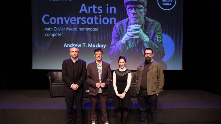 Andrew Mackey standing onstage with LCM staff at the Arts in Conversation event