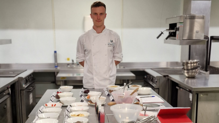 A chef from the University of West London's Food Innovation Centre posing with a selection of ingredients for filming on The Apprentice