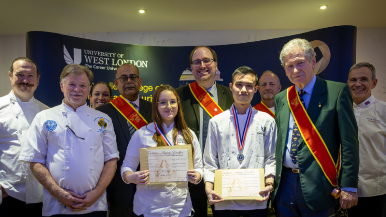 Student chefs posing with Michel Escoffier at the University of West London Entente Cordiale Culinaire event